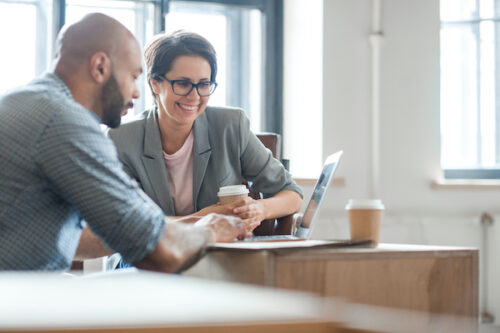 Two enthusiastic professionals look through association websites online for ideas to improve their own site.