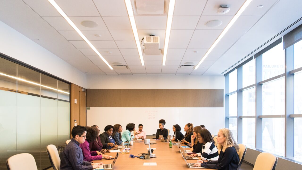 Members gathered in a conference room for a meeting, making notes on important takeaways.