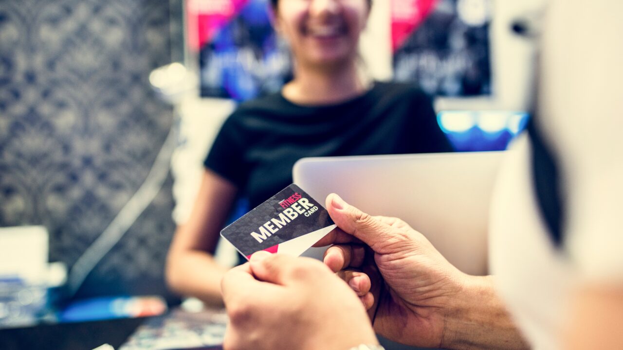 membership card being handed off to woman at computer