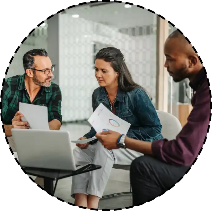 three colleagues reviewing paper documents at a conference table