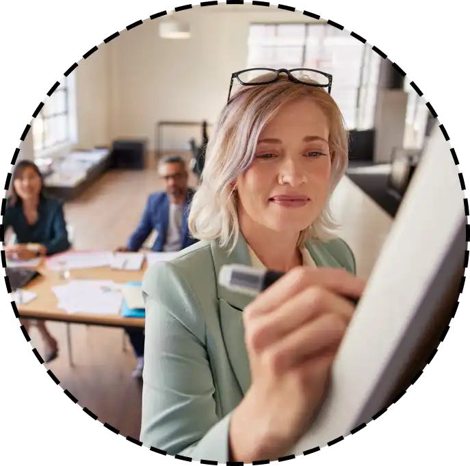 a woman writing on a dry erase board during a meeting