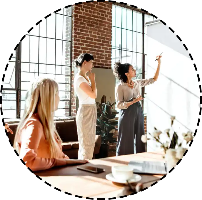 three women draw on an office white board